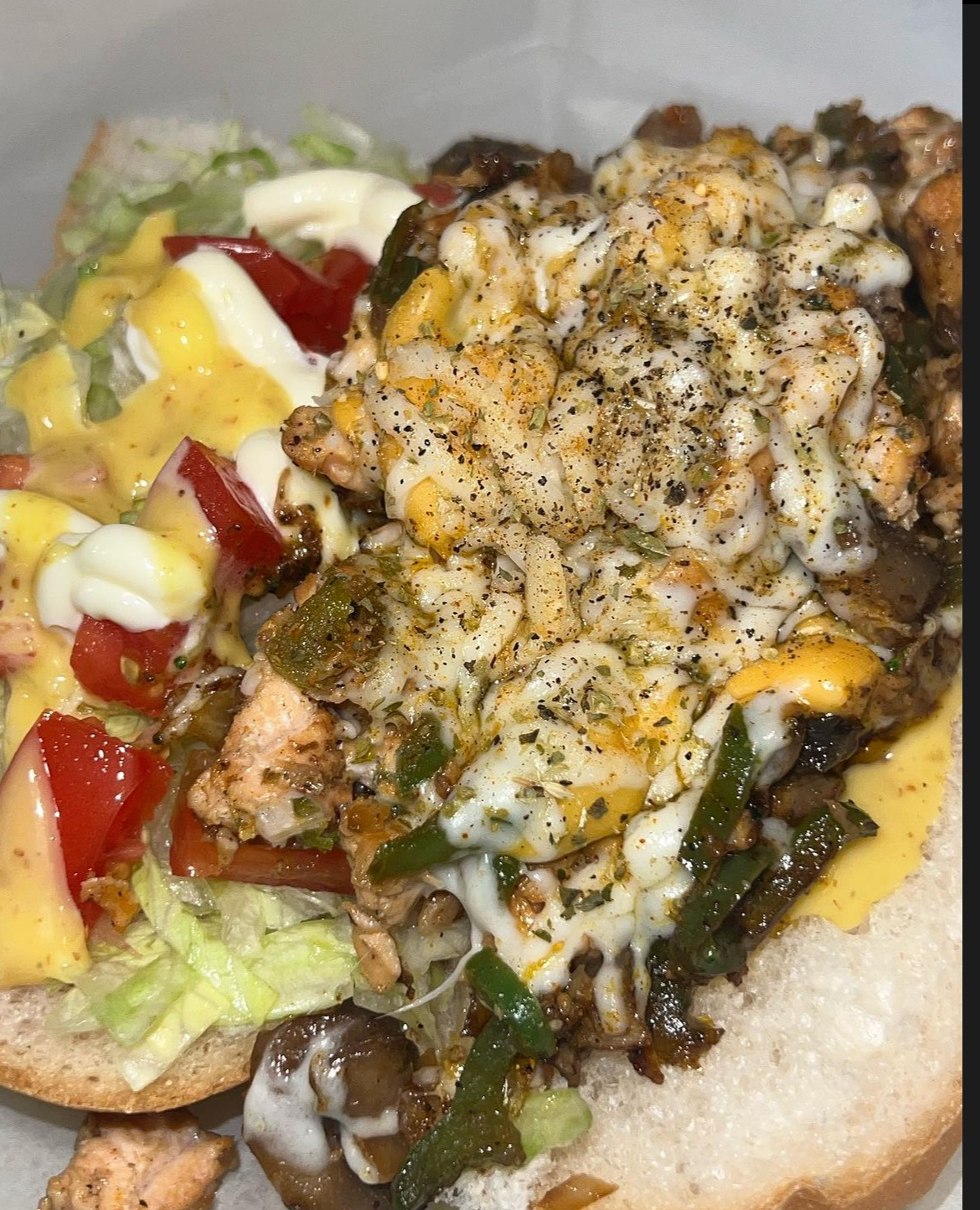 Chicken cheesesteak topped with melted cheese and vegetables