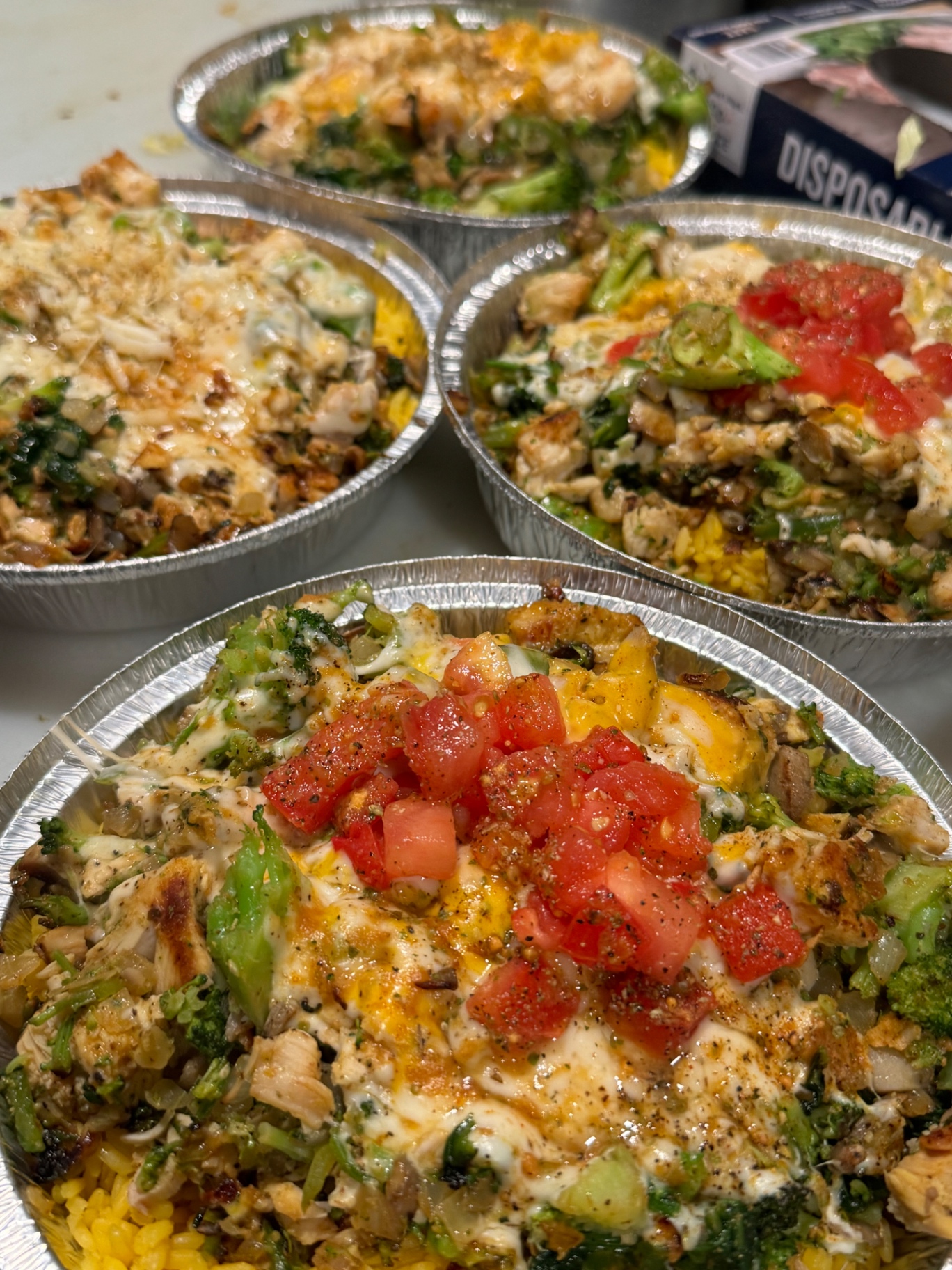 Grilled chicken and broccoli rice bowls topped with melted cheese and diced tomatoes
